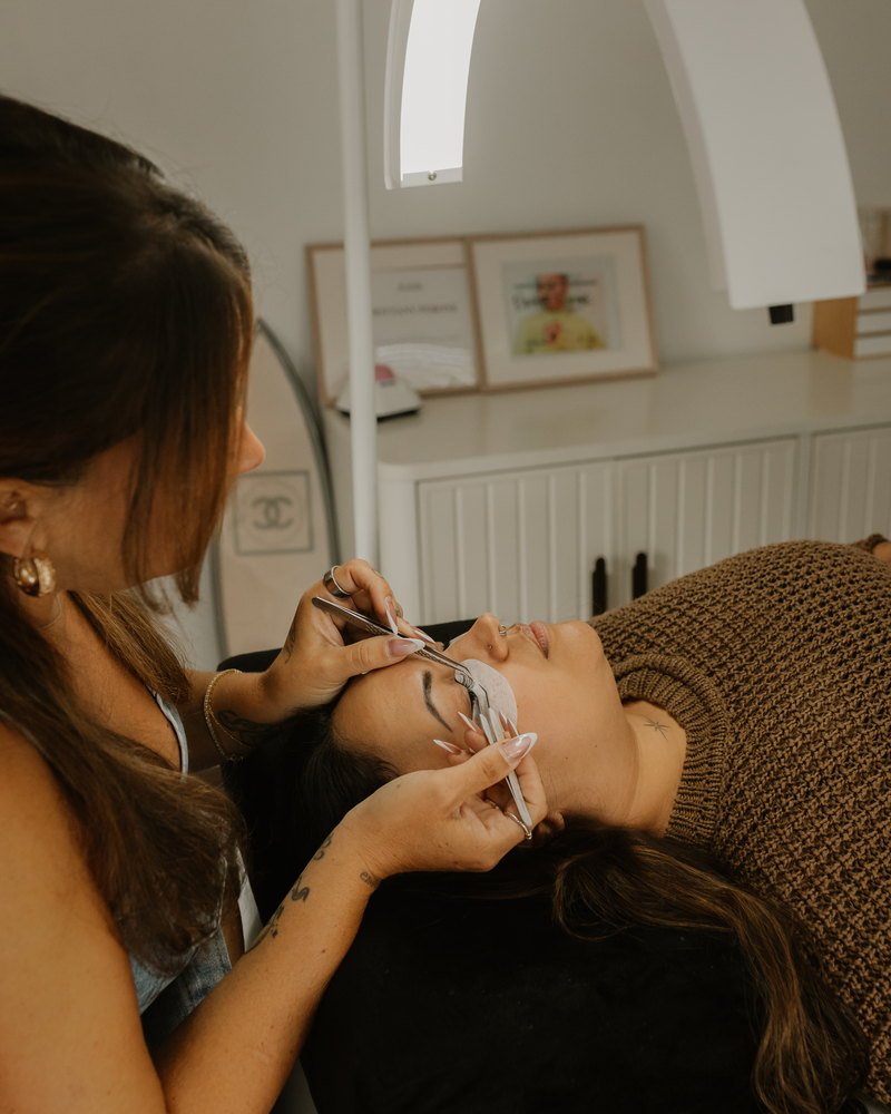 Close view of Brittany isolating a single lash with tweezers while her client rests with eyes closed
